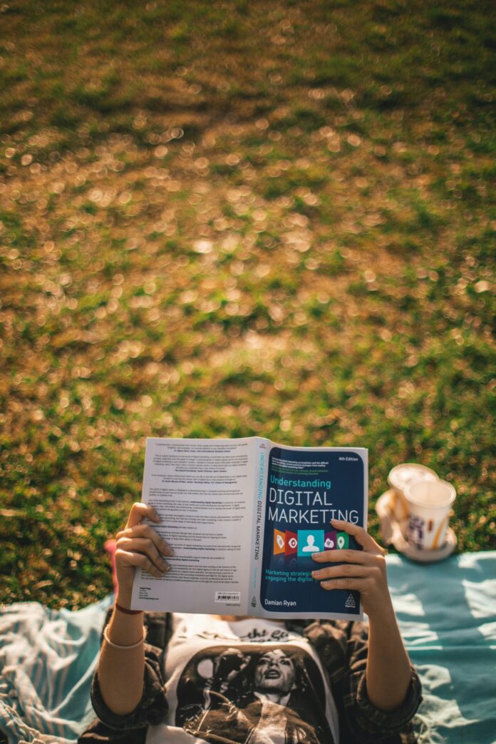 A person laying down reading a digital marketing book.