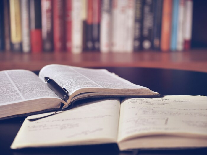 Image of a book, pen, and notebook with study notes on it.