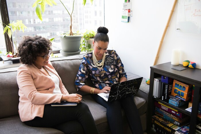 Image of 2 women sitting down and looking at a laptop.