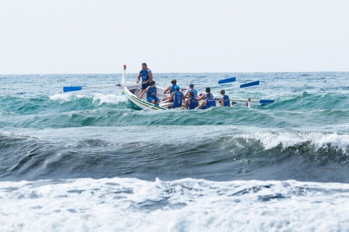 Image of a crew rowing team with a leader leading.